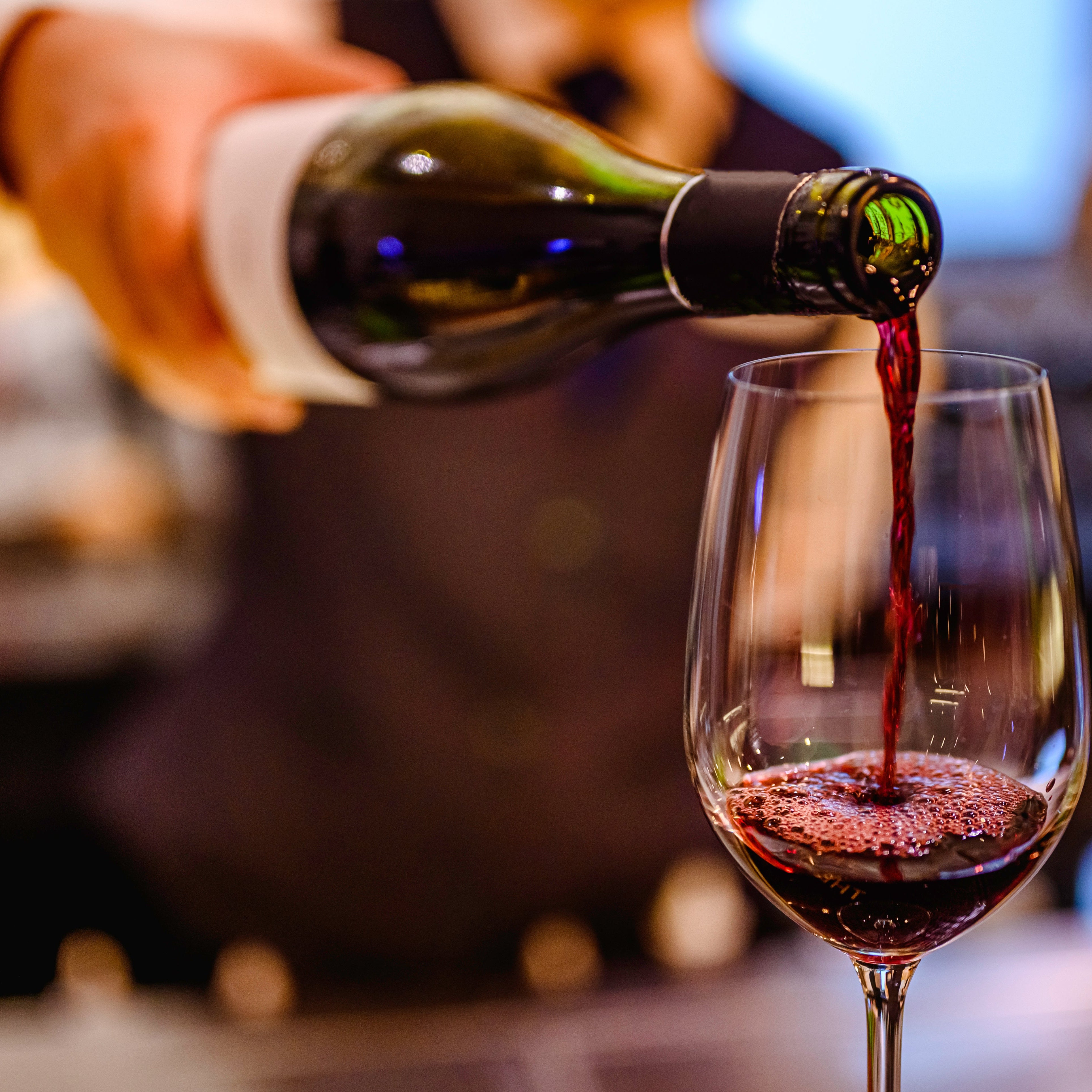 Red wine being poured into a glass with a blurred background